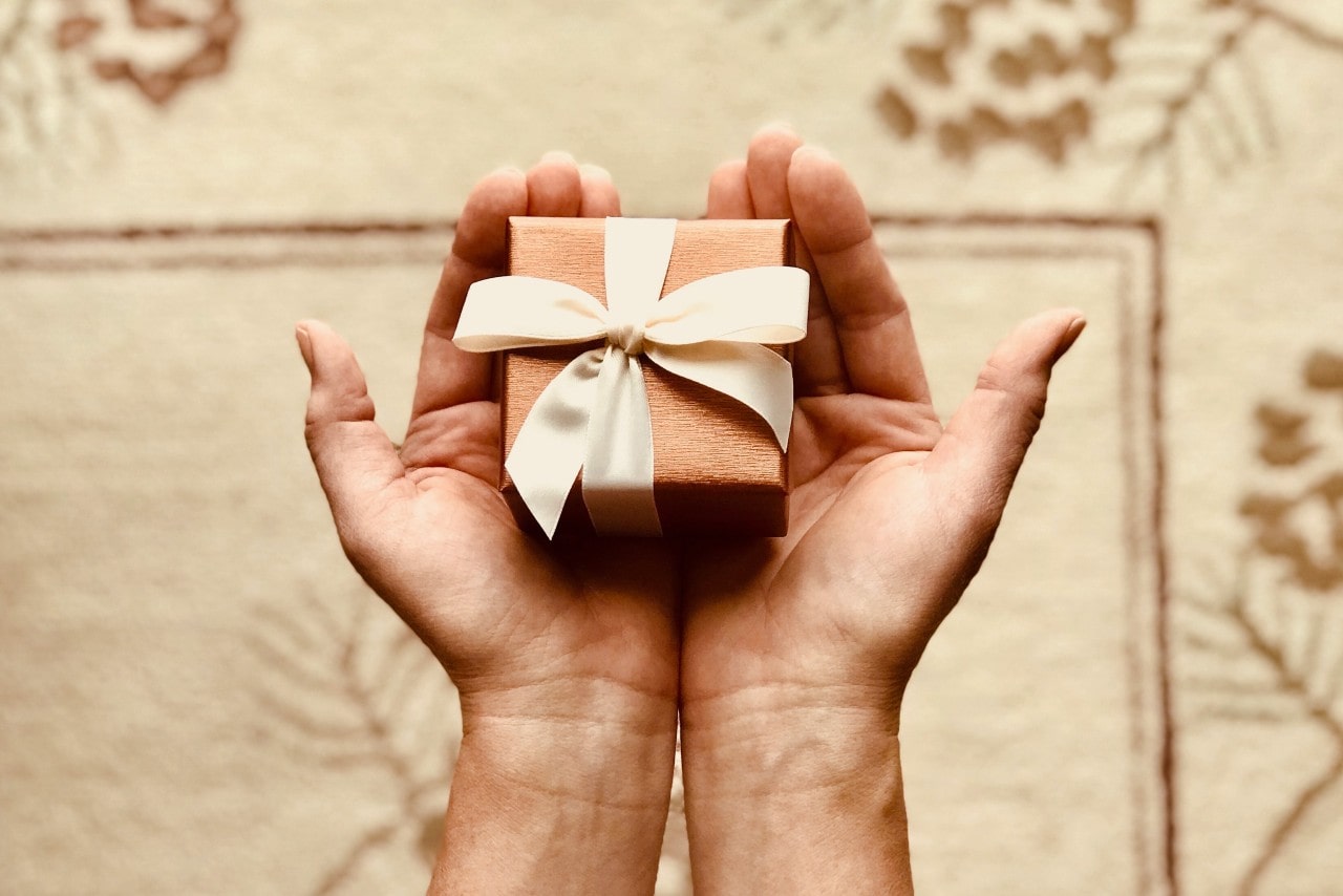 A close-up of a small but impeccable gift box in a person’s hands.