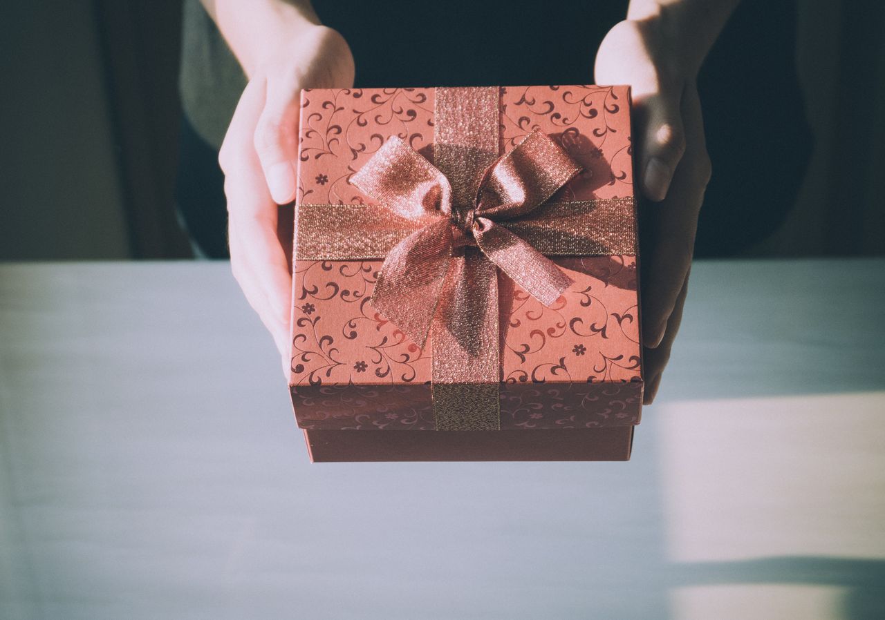 A close-up of a person presenting an elegant yet nondescript gift box.