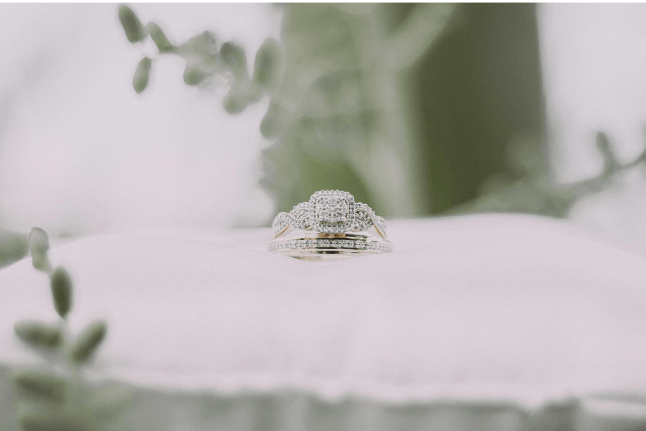a diamond engagement ring and matching wedding band on a white pillow