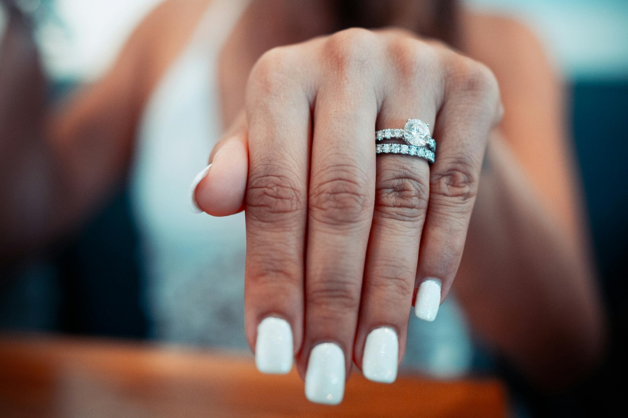 a woman showing off a diamond engagement ring and matching wedding band