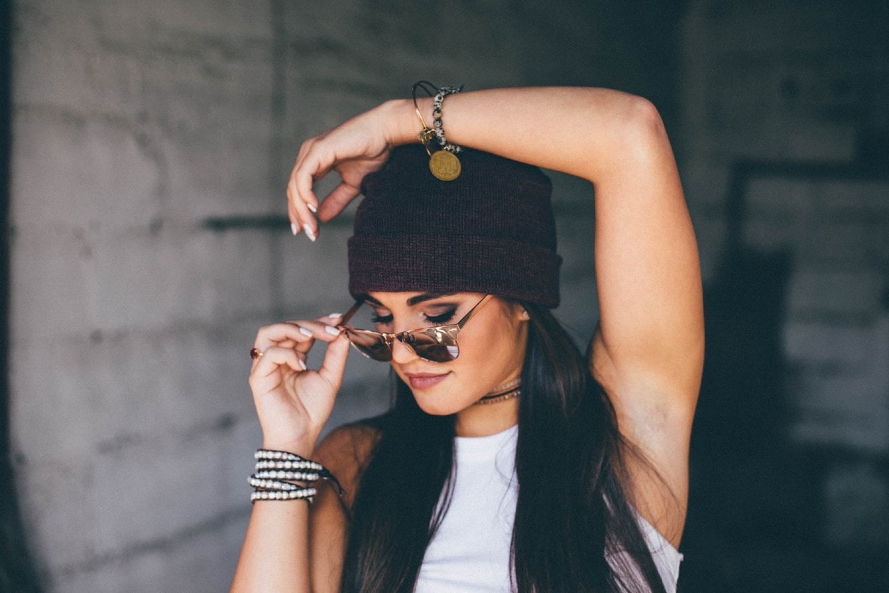 A close-up of a fashionable young woman wearing layered jewelry, striking a pose.