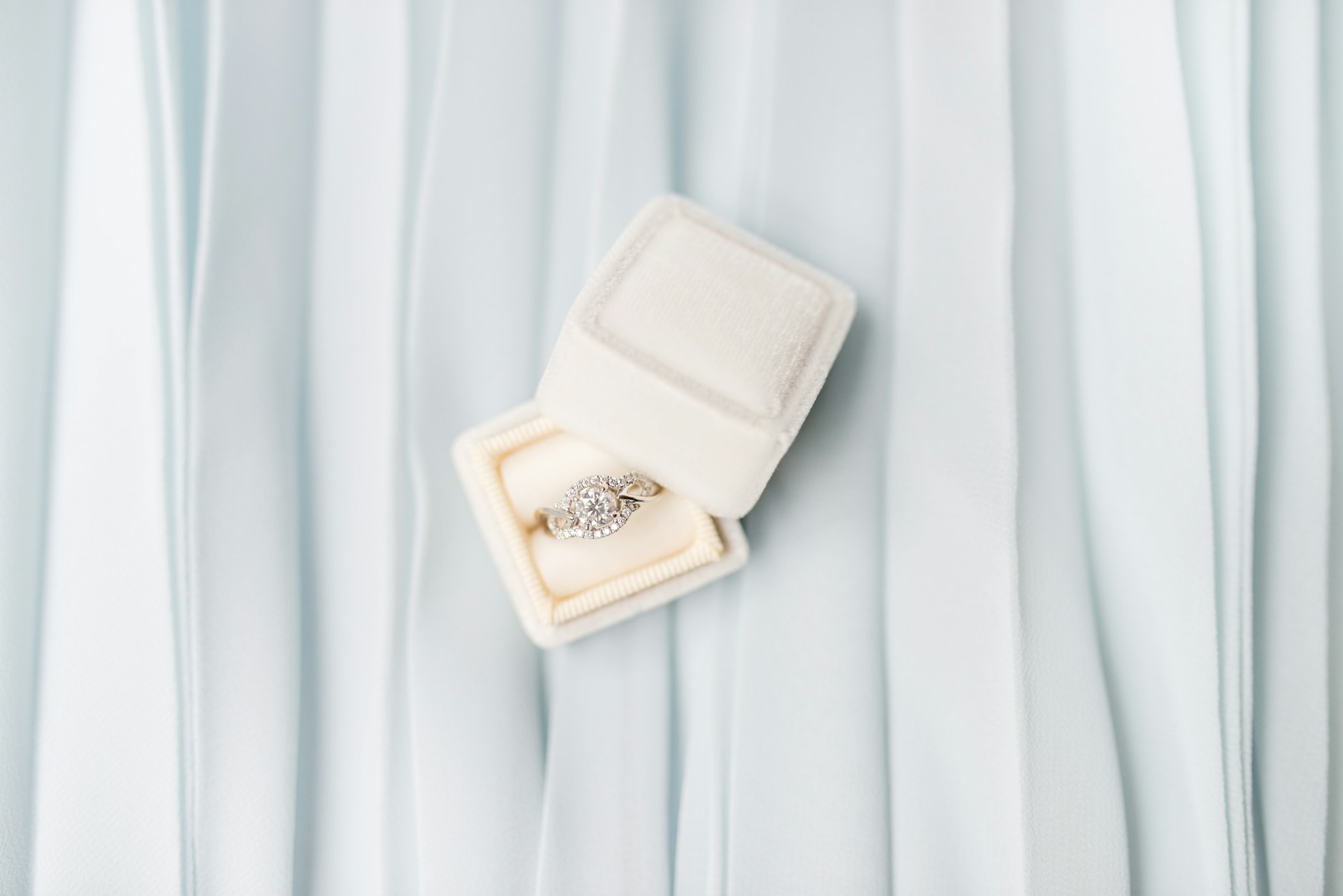 a modern engagement ring sits in a white ring box.