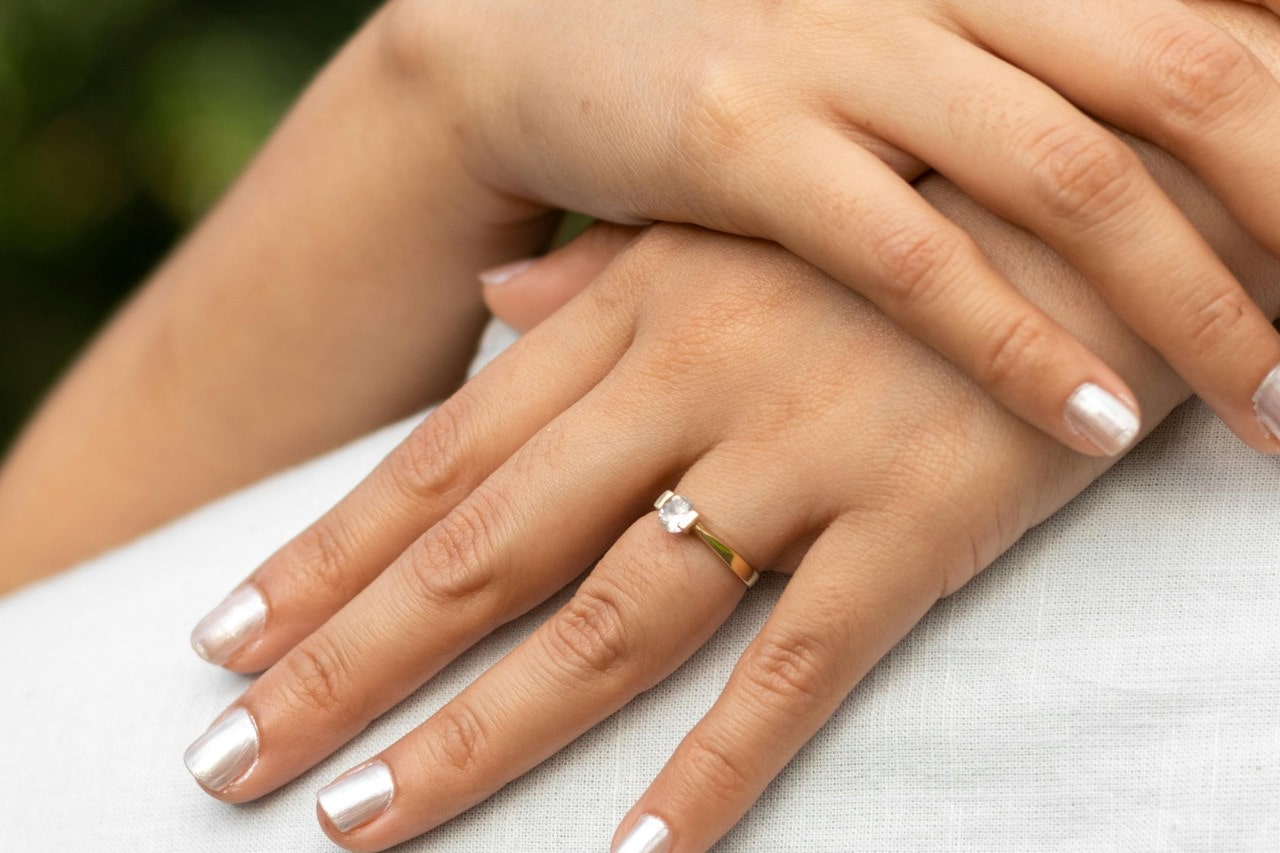 a woman hugs her fiance, showing off her gold engagement ring.