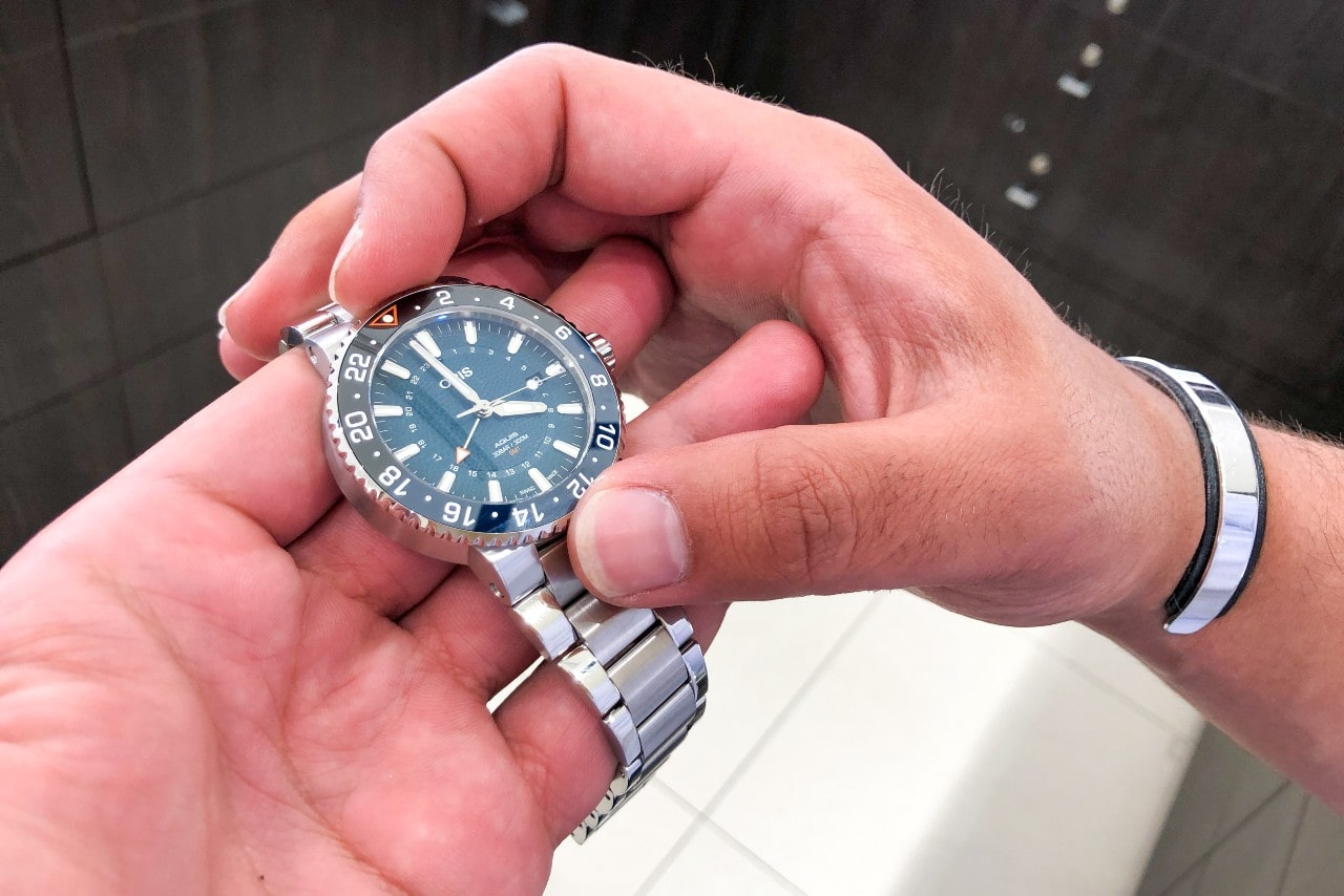 A close-up of a man’s hands holding an Oris watch.