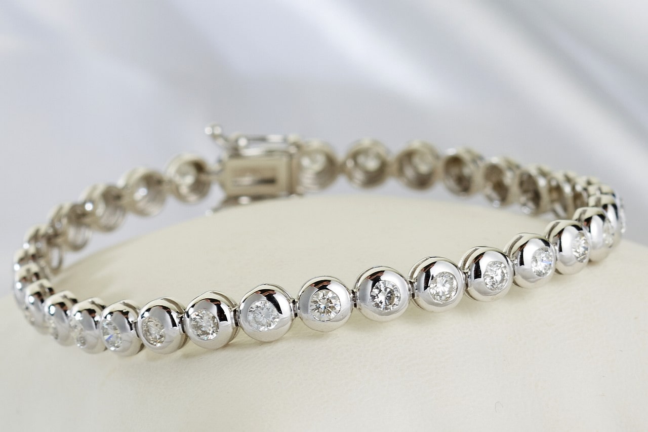 A white gold diamond tennis bracelet with bezel set diamonds