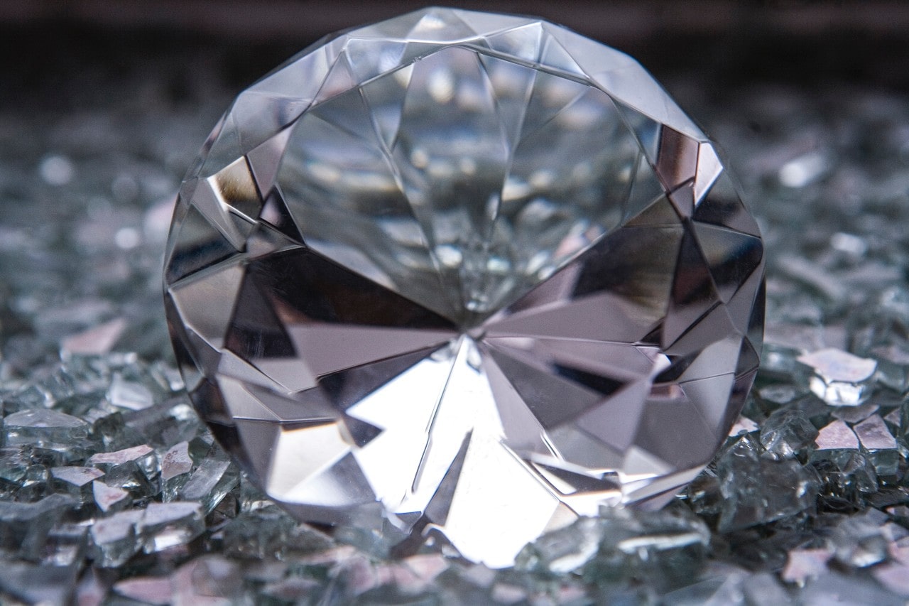 A close-up of a stunning round cut diamond displayed atop diamond shavings.