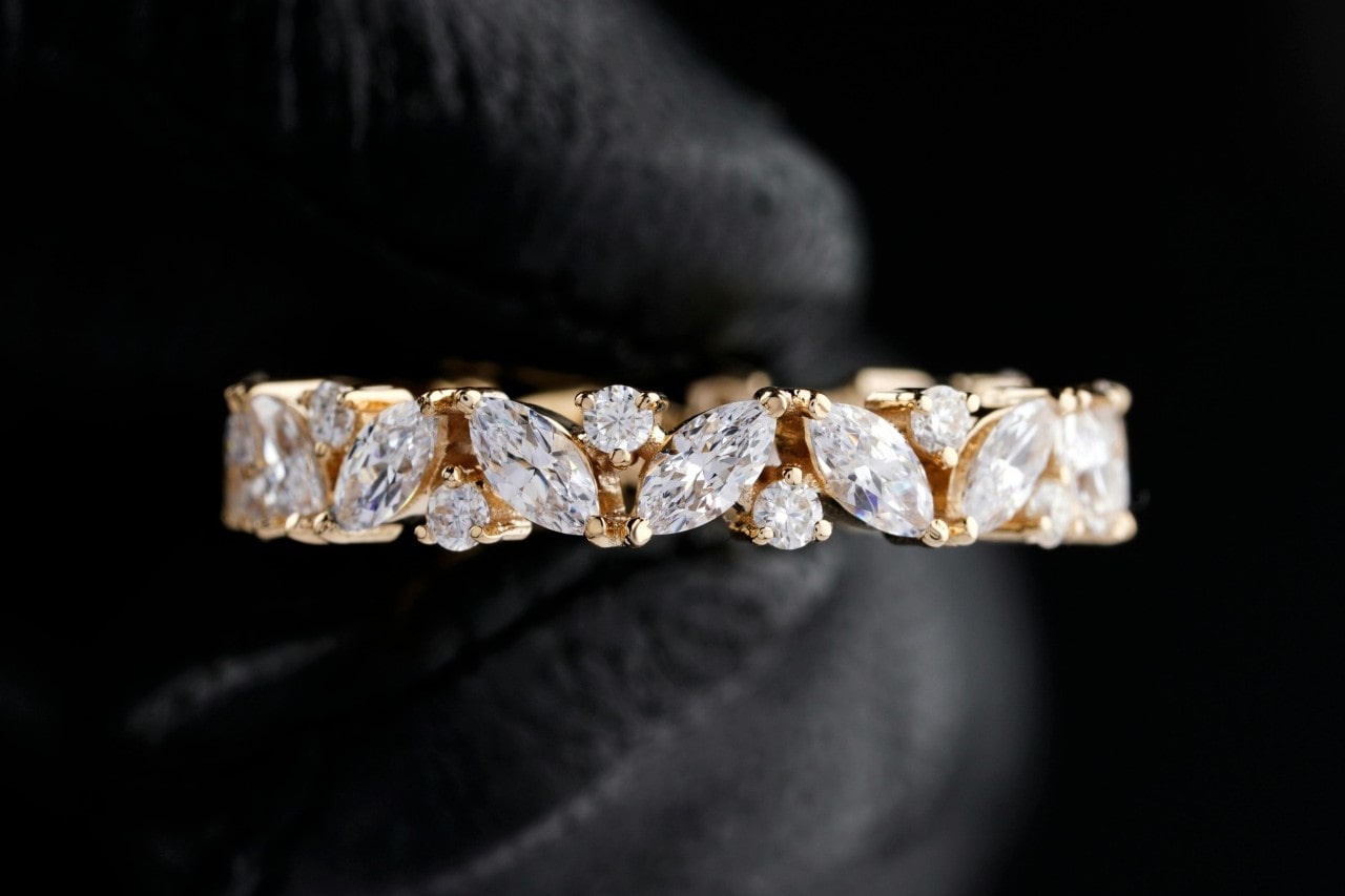 close up image of a diamond wedding band featuring marquise and round cut diamonds