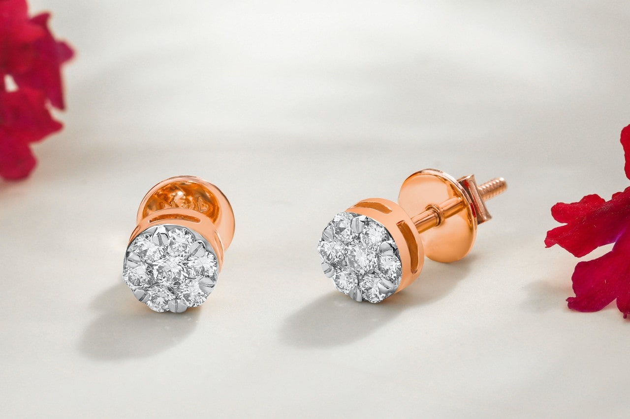 a pair of rose gold diamond halo stud earrings on a beige surface