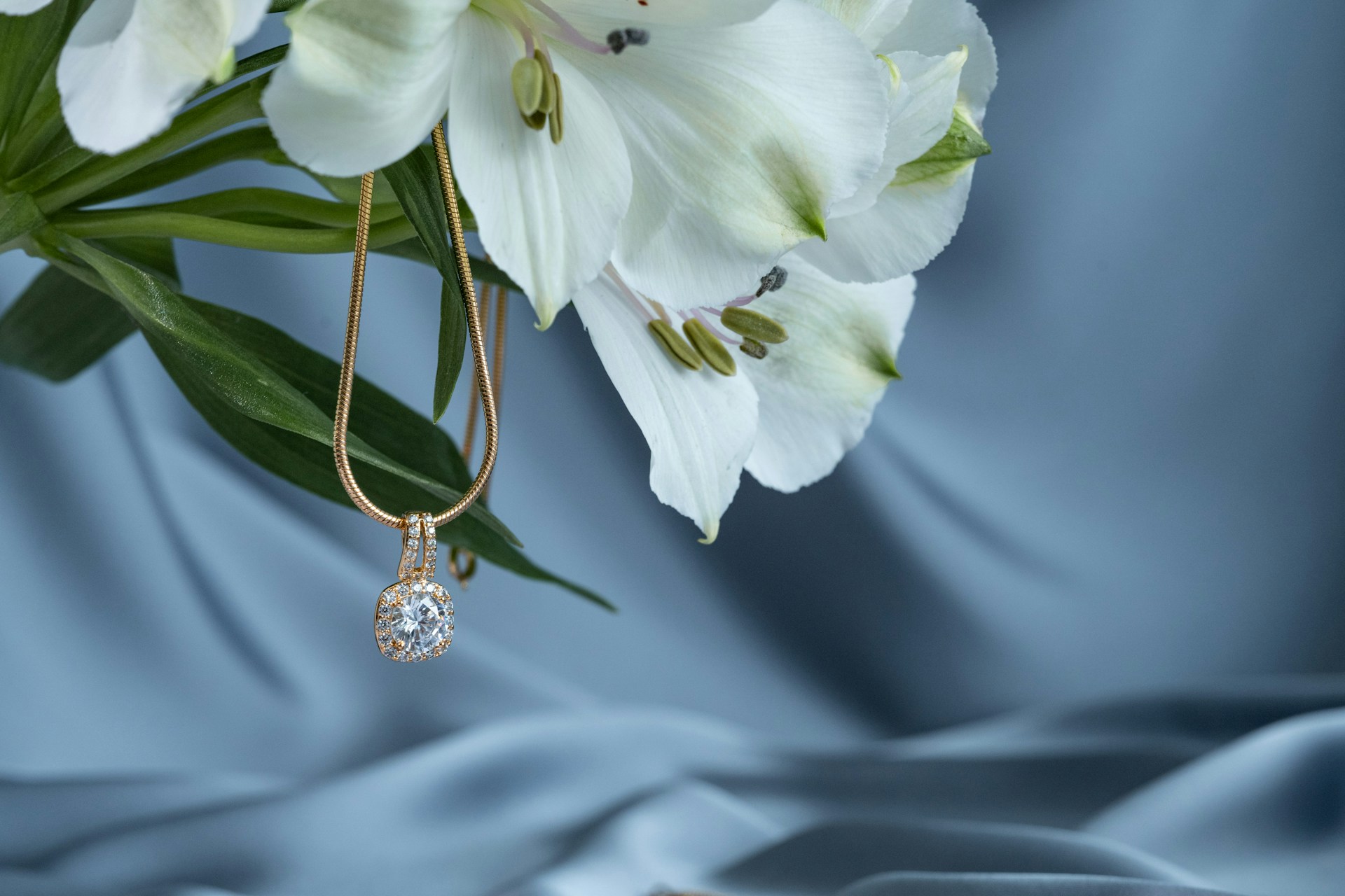 A close-up of a stunning gold pendant draped on a bouquet of lilies.