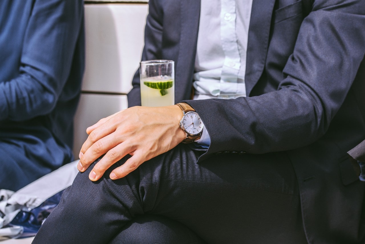 man with dress watch holding fruit drink