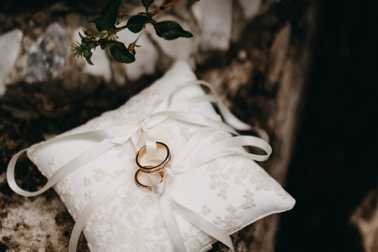 Two elegant wedding bands displayed on a delicate white cushion.